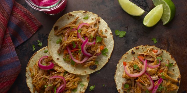 Para servir en tacos, simplemente coloque la carne de cerdo desmechada en mini tortillas de maíz calientes y cubra con las cebollas encurtidas y el cilantro. (Cortesía GOYA)