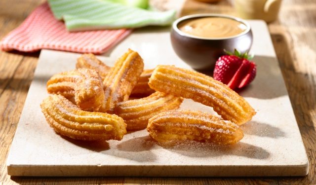 Coloque los churros sobre papel absorbente, luego espolvoree con azúcar y canela. Sírvalos con la salsa.