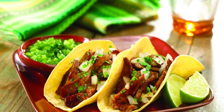 Corta el bistec y sirvelo en las tortillas con cebolla picada, cilantro, y rodajas de limón verde.