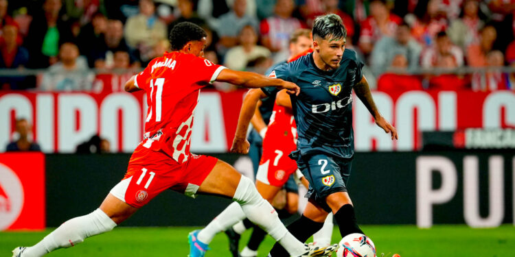 El defensa del Rayo Andrei Ratiu (d) juega un balón ante Arnaut Danjuma, del Girona, durante el partido de la séptima jornada de LaLiga que Girona FC y Rayo Vallecano disputan en el estadio Municipal de Montilivi. EFE/David Borrat