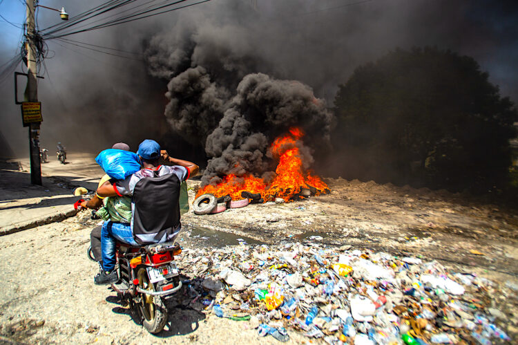 Fotografía de archivo del 19 de  agosto de 2024 de dos hombres se movilizan en motocicleta frente a una barricada con fuego durante una protesta en el barrio Solino, en Puerto Principe (Haití). El Gobierno de Jamaica anunció que da inicio al envío de un número limitado de tropas a la fuerza multinacional, liderada por Kenia, que está desplegada en Haití para restaurar la seguridad. EFE/ Mentor David Lorens