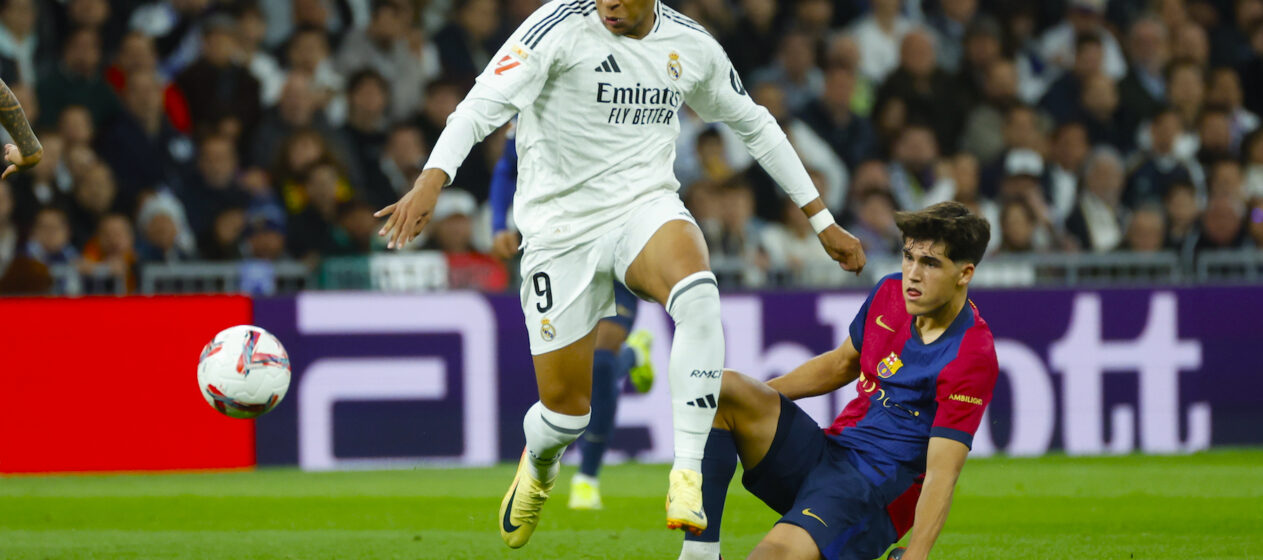 El delantero del Real Madrid Kylian Mbappé (i) lucha con Pau Cubarsí, del FC Barcelona, durante el partido de la jornada 11 de LaLiga EA Sports entre el Real Madrid y el FC Barcelona, este sábado en el estadio Santiago Bernabéu, en Madrid. EFE/Juanjo Martín