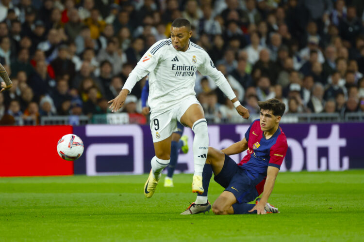 El delantero del Real Madrid Kylian Mbappé (i) lucha con Pau Cubarsí, del FC Barcelona, durante el partido de la jornada 11 de LaLiga EA Sports entre el Real Madrid y el FC Barcelona, este sábado en el estadio Santiago Bernabéu, en Madrid. EFE/Juanjo Martín