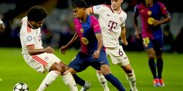 El delantero del FC Barcelona Lamine Yamal (c) se escapa del defensa del Bayern Joshua Kimmich (d), durante el encuentro correspondiente a la fase regular de la Liga de Campeones que disputaron el FC Barcelona y Bayern Munich en el estadio Olímpico Lluis Companys, en Barcelona. EFE/Alejandro García.