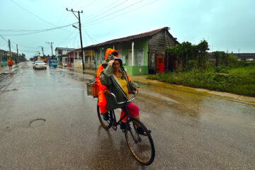 Dos personas se movilizan en bicicleta bajo la lluvia, este miércoles en Surgidero de Batabanó, un puerto pesquero en la provincia occidental de Mayabeque, a unos 50 kilómetros al sur de La Habana (Cuba). Se espera que en las próximas horas Rafael toque tierra en Cuba con categoría dos -de un máximo de cinco- con vientos sostenidos de más de 150 km/h por la costa sur del occidente del país. El Surgidero de Batabanó forma parte de la zona de riesgo. EFE/ Ernesto Mastrascusa