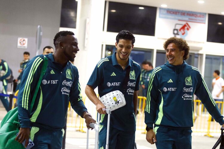 Julian Quiñones (i), Raúl Gímenez (c), y Guillermo Ochoa, jugadores de la selección mexicana de fútbol, hablan durante su llegada al aeropuerto Ramon Villeda Morales, este miércoles, en la ciudad de San Pedro Sula (Honduras). La selección mexicana enfrentará a Honduras en la ida de los cuartos de final de la Nations League de la Concacaf. EFE/ Jose Valle